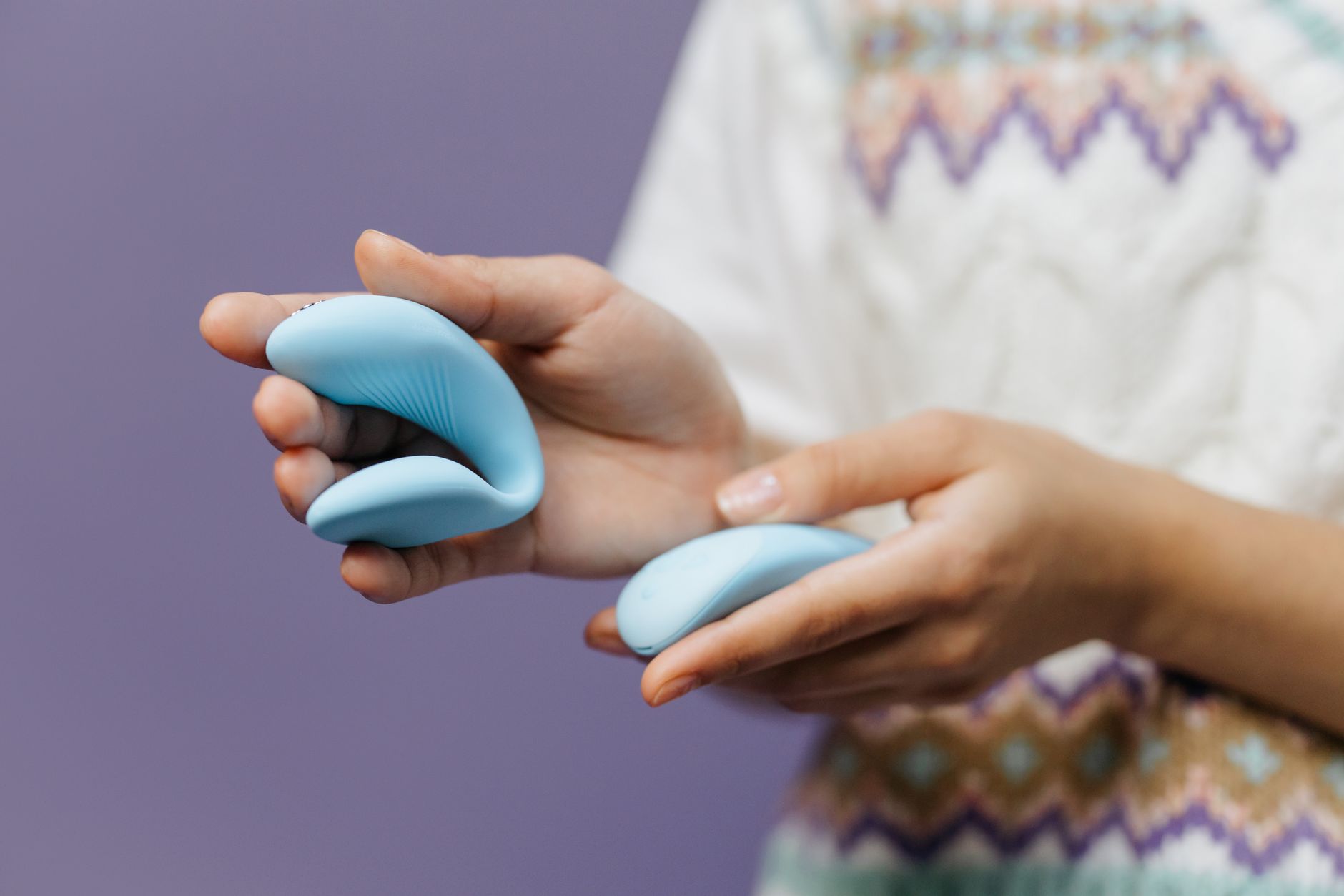Intimate close-up of hands holding a sleek vibrator, representing partnered pleasure and connection
